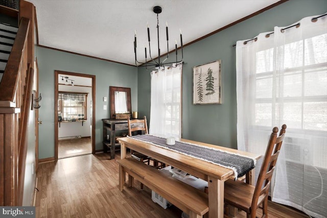 dining space featuring a wealth of natural light, hardwood / wood-style floors, ornamental molding, and a notable chandelier