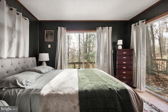 bedroom with multiple windows, crown molding, light hardwood / wood-style floors, and a textured ceiling