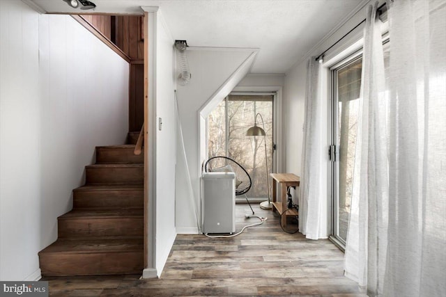 stairs with hardwood / wood-style flooring and crown molding