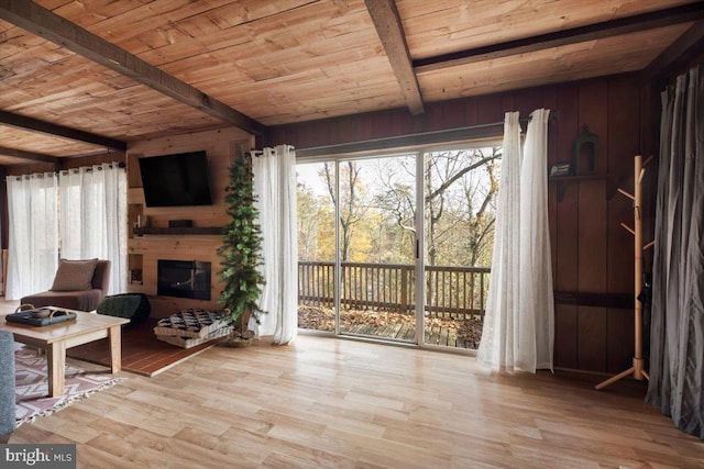 living room featuring beamed ceiling, wood walls, light wood-type flooring, and wooden ceiling