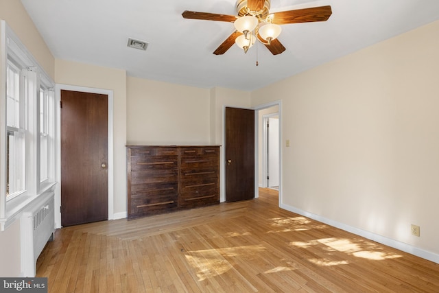 unfurnished bedroom with radiator, ceiling fan, and light hardwood / wood-style floors