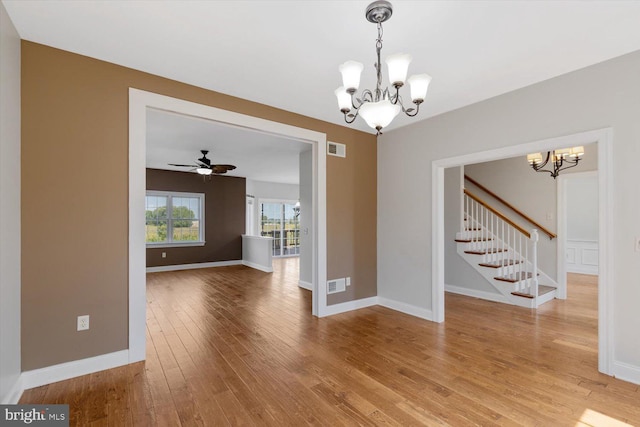 unfurnished dining area featuring wood-type flooring and ceiling fan with notable chandelier