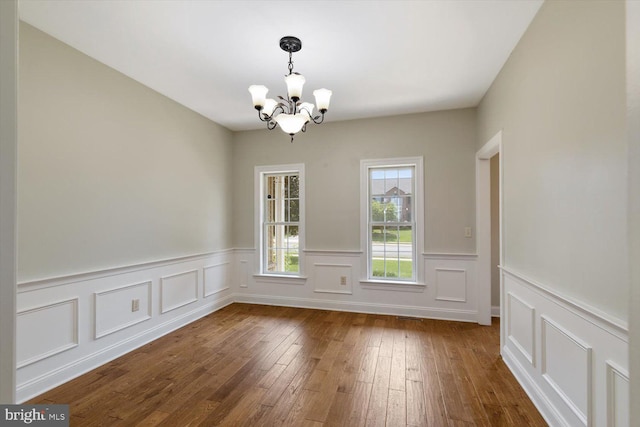 unfurnished dining area featuring dark hardwood / wood-style flooring and a notable chandelier