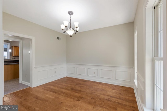 empty room with wood-type flooring and a notable chandelier