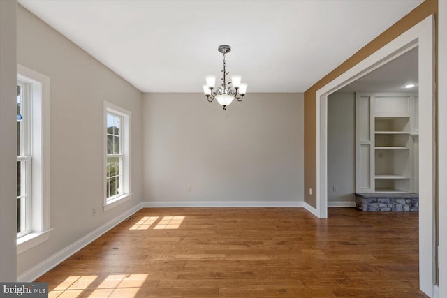 unfurnished dining area featuring an inviting chandelier and wood-type flooring