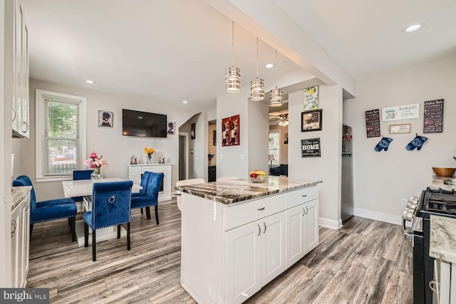 kitchen featuring white cabinets, light wood-type flooring, appliances with stainless steel finishes, and light stone countertops