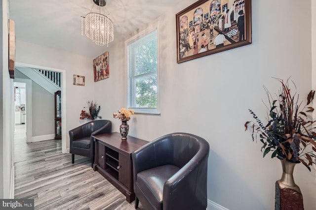 living area featuring light wood-type flooring and a notable chandelier