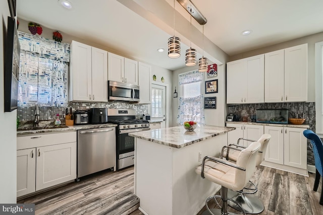 kitchen with stainless steel appliances, white cabinets, and pendant lighting