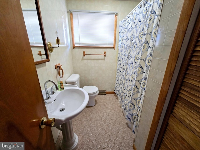 bathroom with tile walls, tile patterned floors, a shower with curtain, sink, and toilet