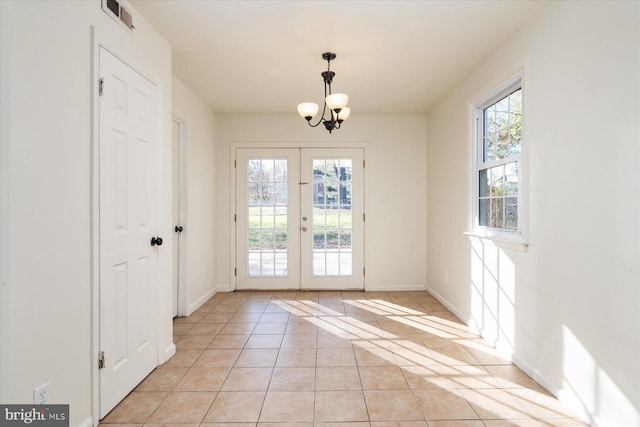 doorway featuring french doors, light tile patterned floors, a healthy amount of sunlight, and a notable chandelier