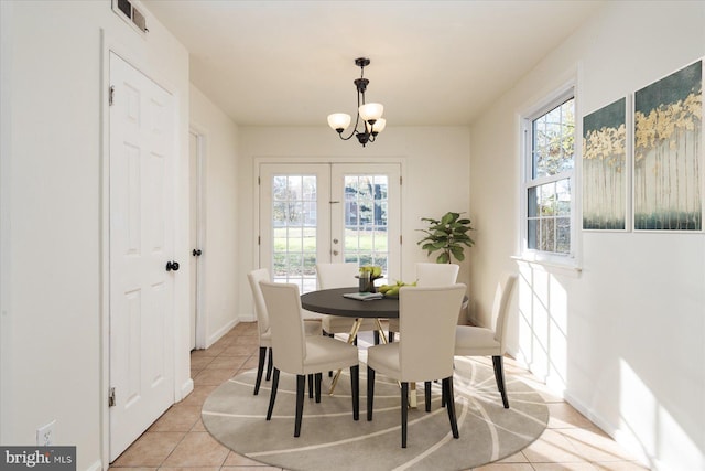dining space with a chandelier, light tile patterned floors, french doors, and baseboards