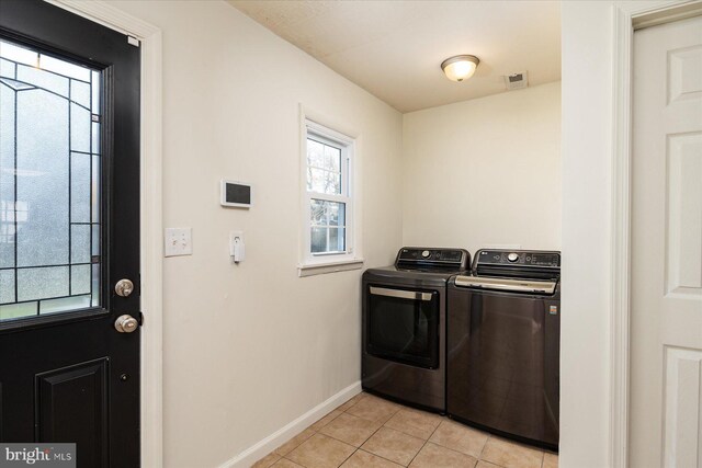 washroom with washer and dryer, baseboards, and light tile patterned floors
