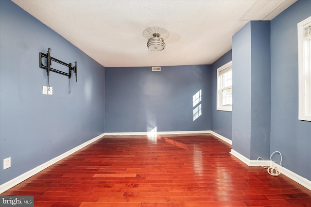 empty room with hardwood / wood-style floors and a textured ceiling