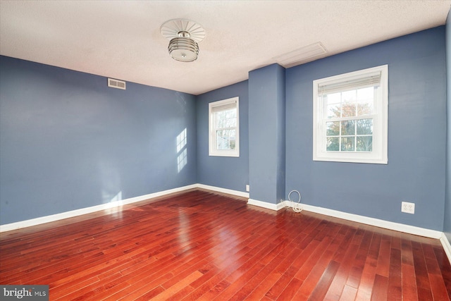 spare room with a healthy amount of sunlight, wood-type flooring, and a textured ceiling