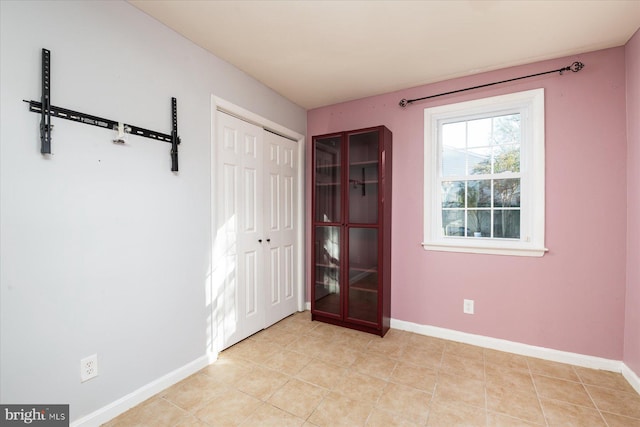 unfurnished bedroom featuring baseboards, a closet, and light tile patterned flooring