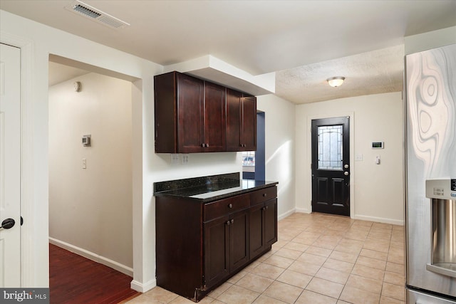 kitchen featuring baseboards, dark brown cabinetry, and light tile patterned flooring