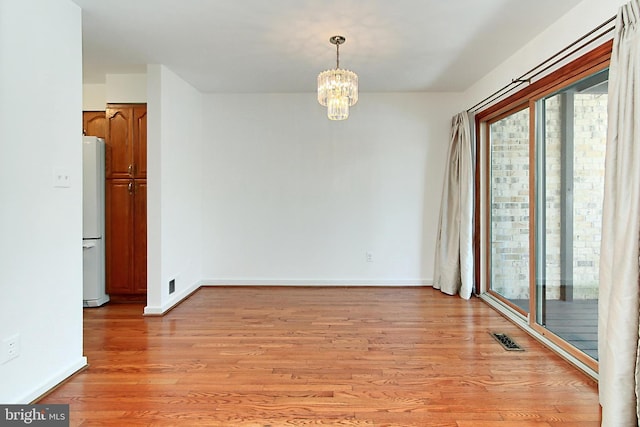 spare room featuring light hardwood / wood-style floors and a notable chandelier