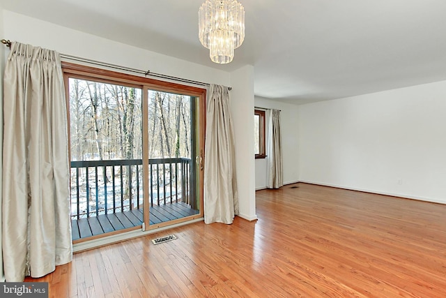 empty room featuring light wood-type flooring and an inviting chandelier