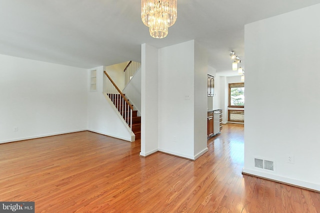 spare room featuring an inviting chandelier and light wood-type flooring