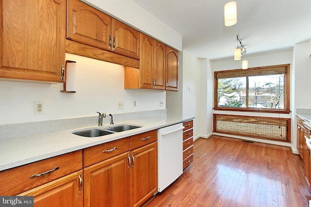 kitchen featuring decorative light fixtures, sink, dishwasher, and light hardwood / wood-style floors