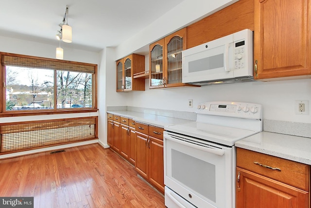 kitchen featuring light wood-type flooring, light stone counters, and white appliances