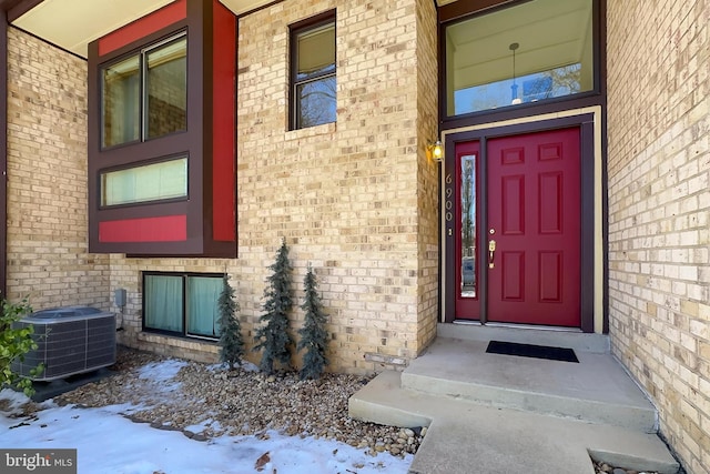 snow covered property entrance featuring central AC unit