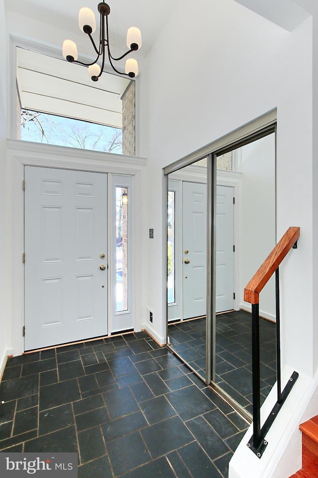 foyer featuring a healthy amount of sunlight, a notable chandelier, and a towering ceiling