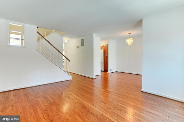 spare room with light hardwood / wood-style floors and an inviting chandelier