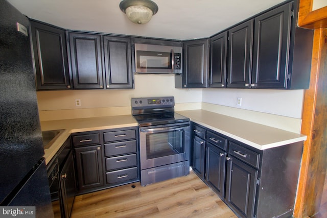 kitchen with appliances with stainless steel finishes and light hardwood / wood-style floors