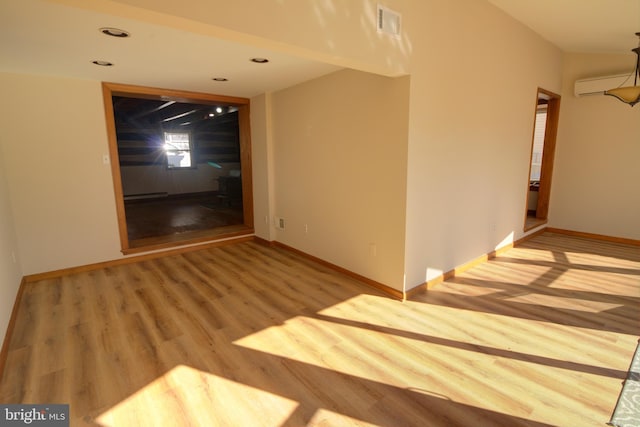 unfurnished room featuring a wall unit AC and wood-type flooring