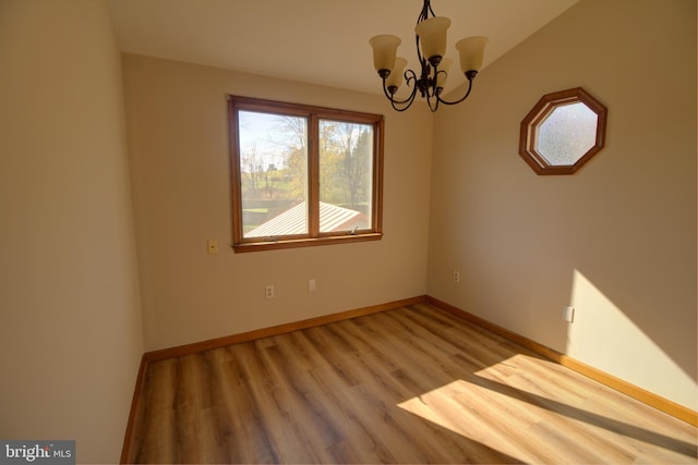 unfurnished room featuring light hardwood / wood-style flooring and a chandelier