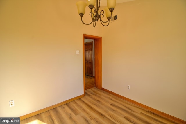 spare room with hardwood / wood-style floors and a chandelier