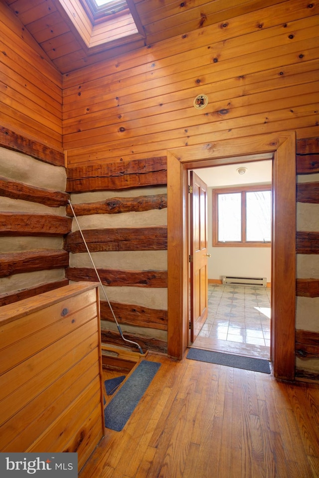 hall with wooden ceiling, baseboard heating, light wood-type flooring, and lofted ceiling with skylight