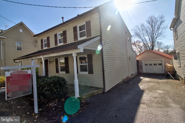 view of front of property with a garage, covered porch, and an outdoor structure