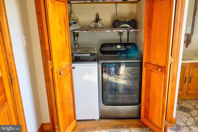 laundry area with washing machine and dryer and light tile patterned floors