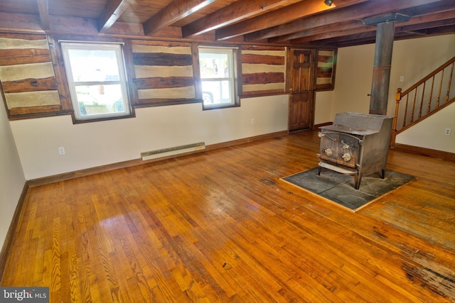 unfurnished living room with hardwood / wood-style floors, a healthy amount of sunlight, a wood stove, and beam ceiling