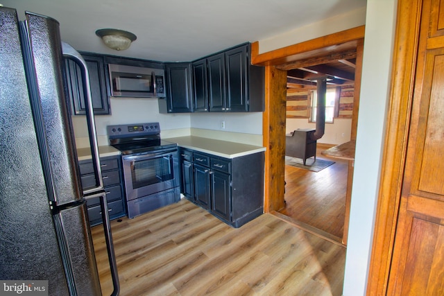 kitchen with stainless steel appliances, light hardwood / wood-style floors, and blue cabinets