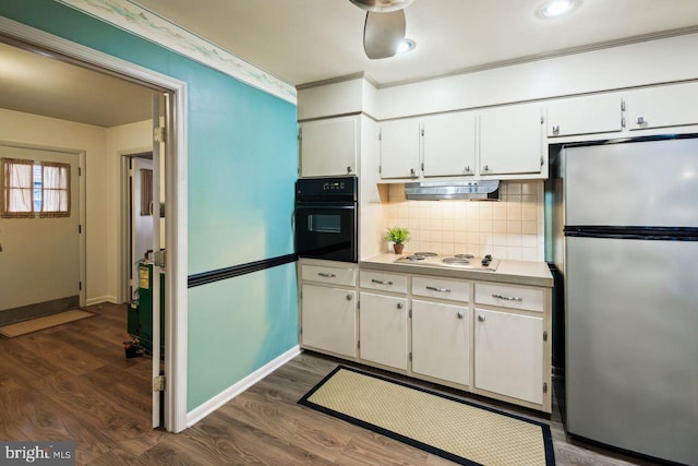 kitchen featuring dark wood-type flooring, black oven, stainless steel refrigerator, and white cabinetry