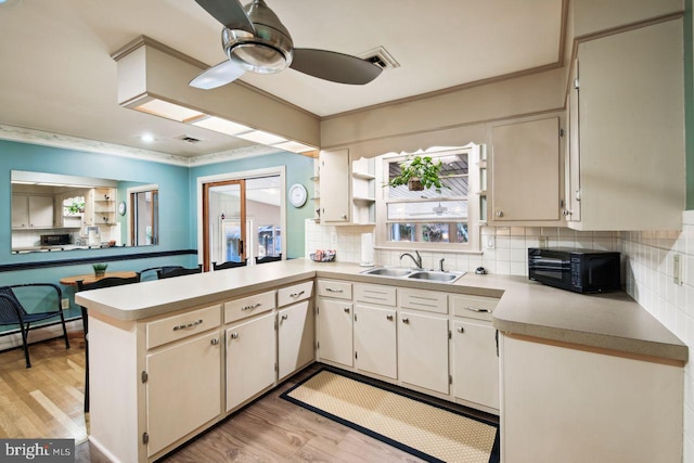 kitchen featuring kitchen peninsula, light hardwood / wood-style flooring, sink, and tasteful backsplash