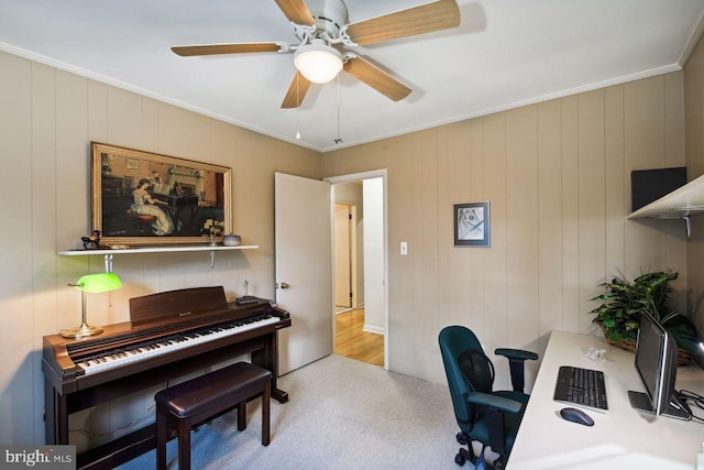 home office with ornamental molding, light carpet, wooden walls, and ceiling fan