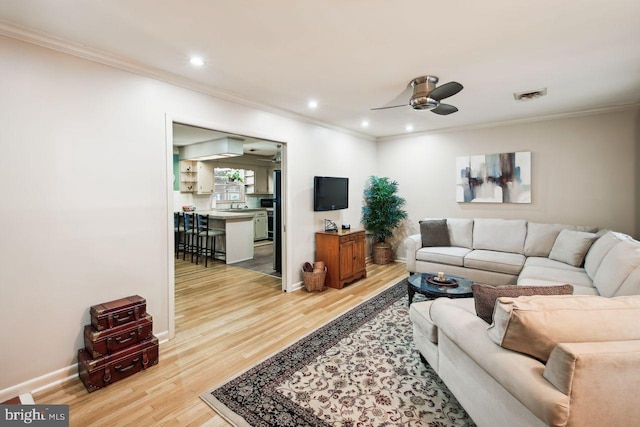 living room featuring crown molding, ceiling fan, and light hardwood / wood-style flooring