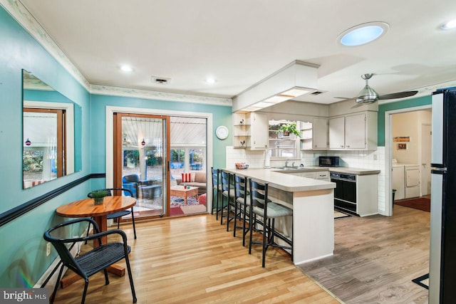 kitchen featuring white cabinetry, separate washer and dryer, kitchen peninsula, and light wood-type flooring