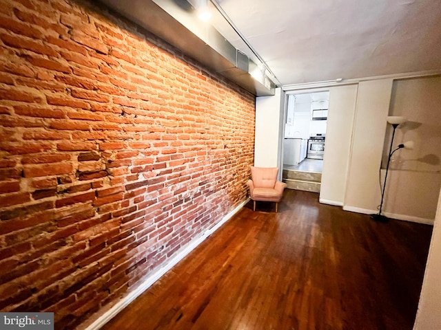 corridor featuring dark wood-type flooring and brick wall