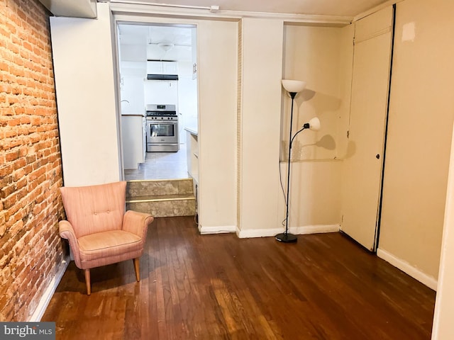 unfurnished room featuring dark hardwood / wood-style flooring and brick wall