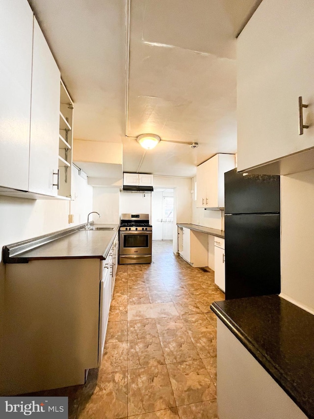 kitchen with black fridge, white cabinets, and stainless steel range with gas stovetop