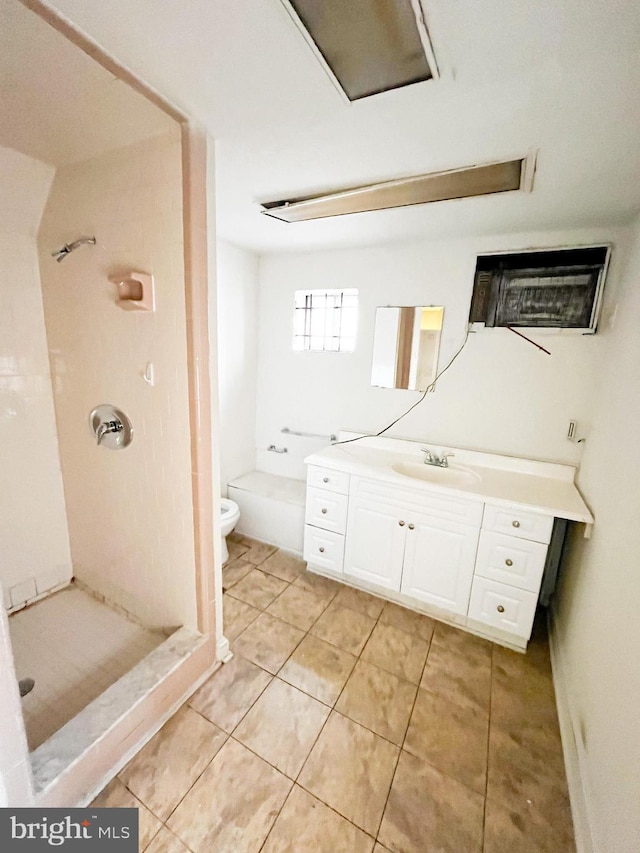 bathroom with tiled shower, vanity, toilet, and tile patterned flooring