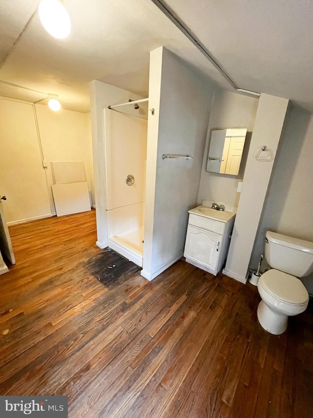 bathroom featuring wood-type flooring, vanity, toilet, and walk in shower