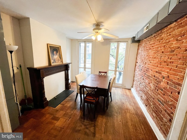 dining room featuring ceiling fan, dark hardwood / wood-style floors, and brick wall