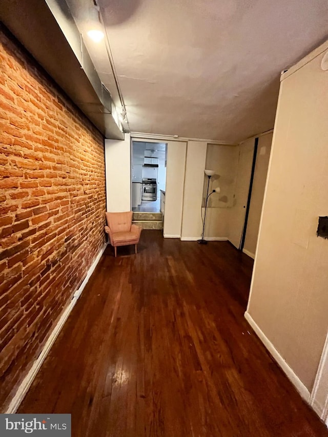 hall with dark hardwood / wood-style floors and brick wall