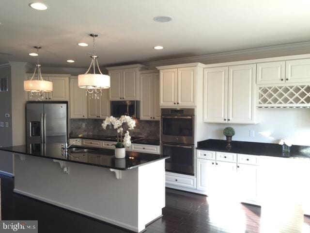 kitchen with white cabinets, hanging light fixtures, a breakfast bar area, and stainless steel appliances